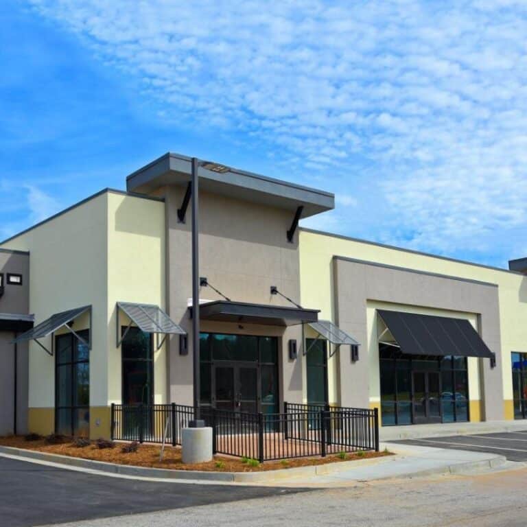 A clean, well-maintained commercial building with neutral tones, black awnings, and glass entrances, reflecting the effectiveness of commercial pressure washing services.